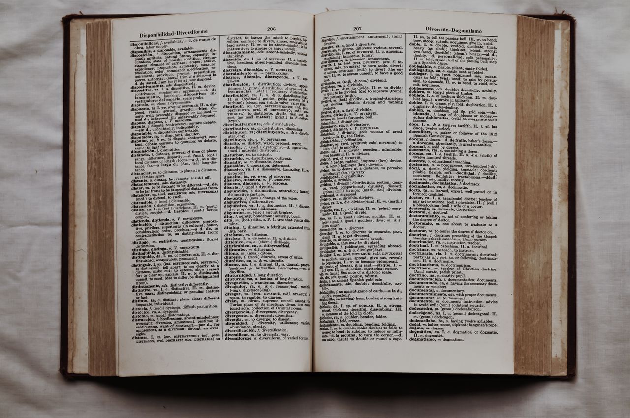 Close-up of an open dictionary showing English and Spanish translations, flat lay view.